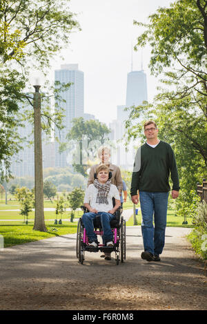 Parents pushing paraplegic daughter in wheelchair Stock Photo