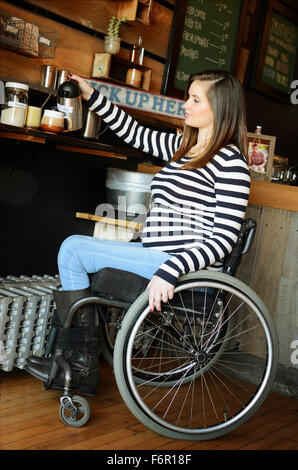 Paraplegic woman in wheelchair pouring coffee in cafe Stock Photo