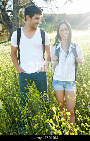 Couple carrying backpacks in field Stock Photo
