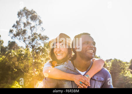 Man carrying girlfriend piggyback outdoors Stock Photo