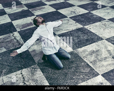 Conceptual, humble man and checkered ground Stock Photo