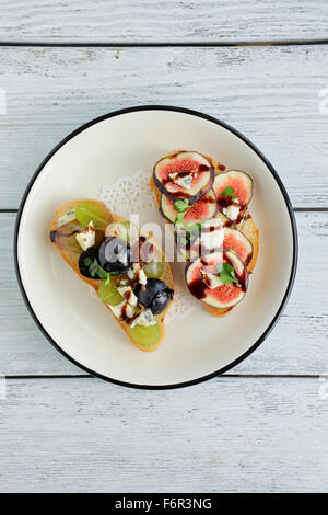 bruschetta with fruits and cheese on plate Stock Photo