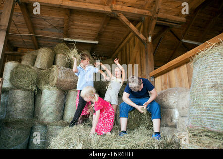 Group of children in stable playing with hay Stock Photo