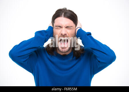 Desperate hysterical angry man with long hair closed ears by hands and screaming with opened mouth Stock Photo