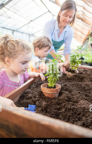 Female gardener and children in greenhouse Stock Photo
