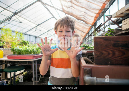 Boy in greenhouse showing his dirty hands Stock Photo