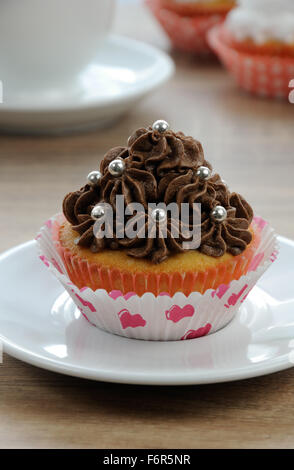Muffin decorated with chocolate cream in paper packaging Stock Photo