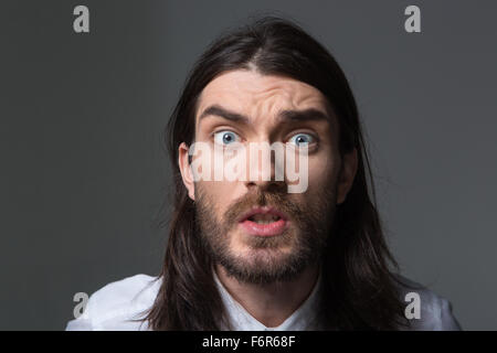 Portrait of angry man with beard and long hair looking at camera isolated on a black background Stock Photo