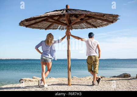 Young couple standing under parasol on beach Stock Photo