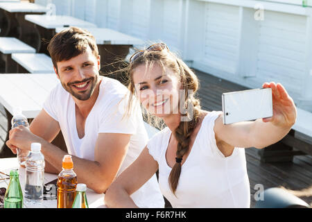 Young couple taking a self portrait in beach bar Stock Photo