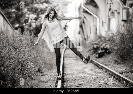 Young woman laughing, standing on train tracks Stock Photo