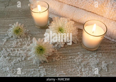 Spa composition with white towels, candles, flowers and bath salt on wooden table Stock Photo