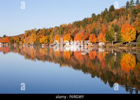 Brilliant fall colors reflected in a smooth, calm lake.  Photographed in morning light. Stock Photo