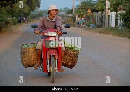 Luang Prabang, Laos. Man riding his scooter with basket full of vegetables on the street of Luang Prabang Stock Photo