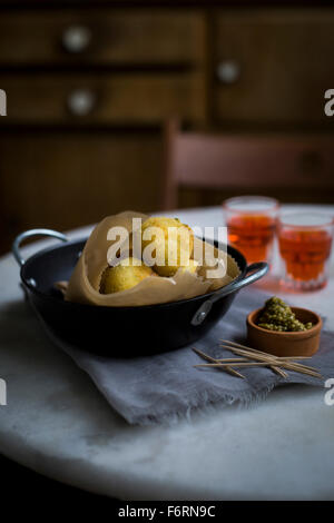 Cheese balls with herbal mustard on marble table with vintage kitchen cupboard in background Stock Photo