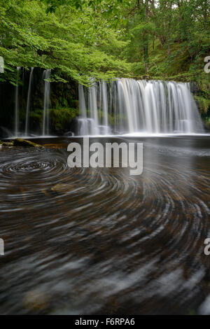 Sgwd Ddwli Uchaf surrounded by vibrant green foliage on a summer afternoon in the Brecon Beacons, Wales. Stock Photo