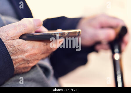 closeup of an old caucasian man with a walking stick in his hand using a smartphone Stock Photo