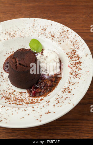 chocolate cake with ice cream and topped with berries served in a white plate Stock Photo