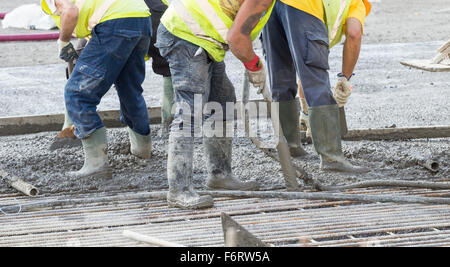 Workman removing air bubbles from newly poured concrete with vibrating poker Stock Photo