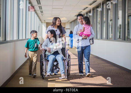 Nurse with patient and family in hospital hallway Stock Photo