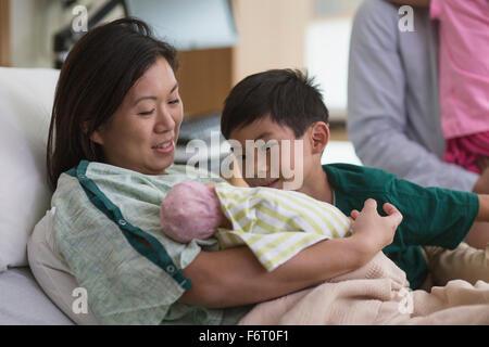 Family admiring newborn baby in hospital room Stock Photo