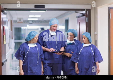 Surgeons using digital tablet in hospital hallway Stock Photo