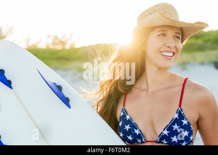 Hispanic woman carrying surfboard on beach Stock Photo