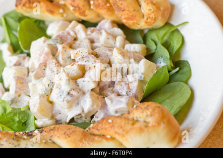 Potato salad on bed of spinach greens with bread stick twists Stock Photo