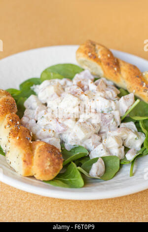 Potato salad on bed of spinach greens with bread stick twists Stock Photo