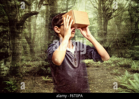 Mixed race boy peering in box in forest