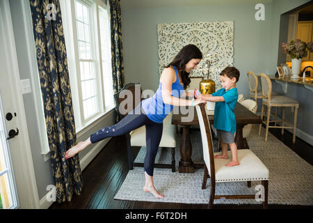 Mother stretching with son in dining room Stock Photo