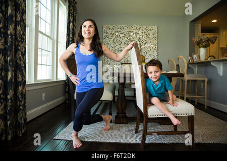 Mother stretching with son in dining room Stock Photo