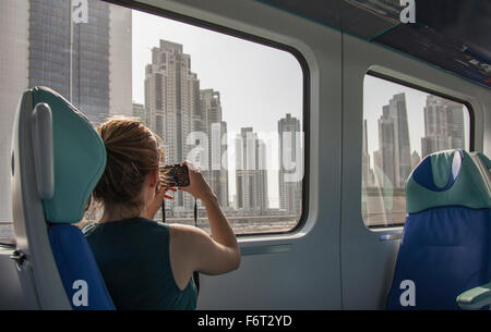 Caucasian woman photographing Dubai cityscape on train, Dubai Emirate, United Arab Emirates Stock Photo
