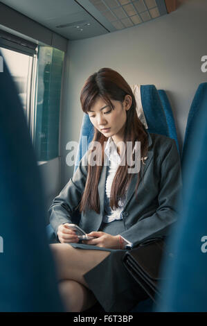 Chinese businesswoman using cell phone on airplane Stock Photo