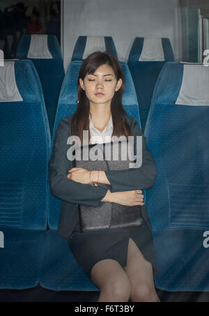 Chinese businesswoman napping on airplane Stock Photo