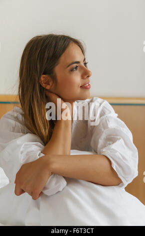 Caucasian woman sitting on bed Stock Photo