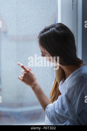 Caucasian woman looking out window Stock Photo