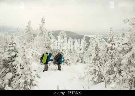 Caucasian hikers walking in snowy forest Stock Photo