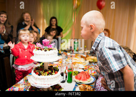 Caucasian boy blowing candles on birthday cake Stock Photo