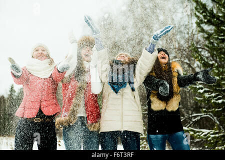 Caucasian girls tossing snow in air Stock Photo