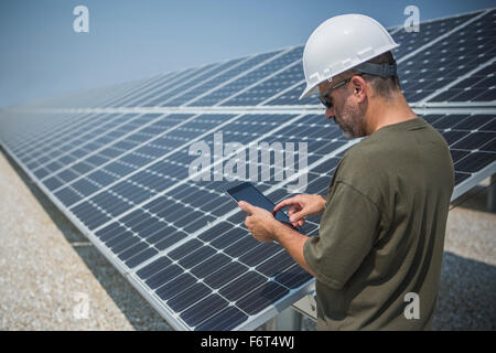 Caucasian technician using digital tablet near solar panels Stock Photo