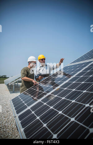 Caucasian technicians examining solar panels Stock Photo