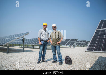 Caucasian technicians standing near solar panels Stock Photo