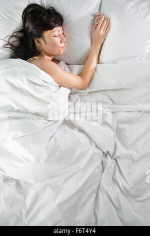 Mixed race woman sleeping in bed Stock Photo
