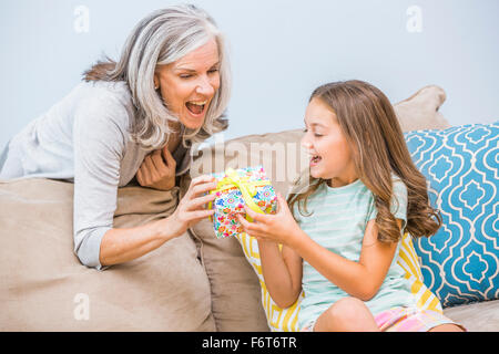 Caucasian girl giving grandmother a gift in living room Stock Photo