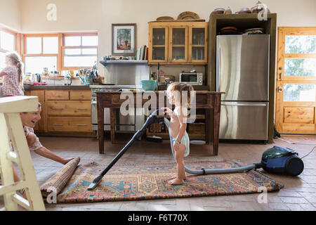 Caucasian brother and sister vacuuming rug Stock Photo