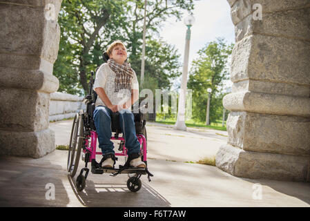 Paraplegic woman in wheelchair under stone arch Stock Photo