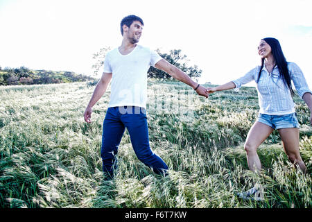Couple holding hands in field Stock Photo