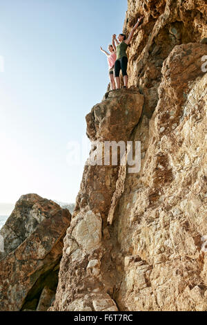 Climbers cheering on rock formation Stock Photo
