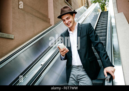 Caucasian businessman using cell phone on escalator Stock Photo